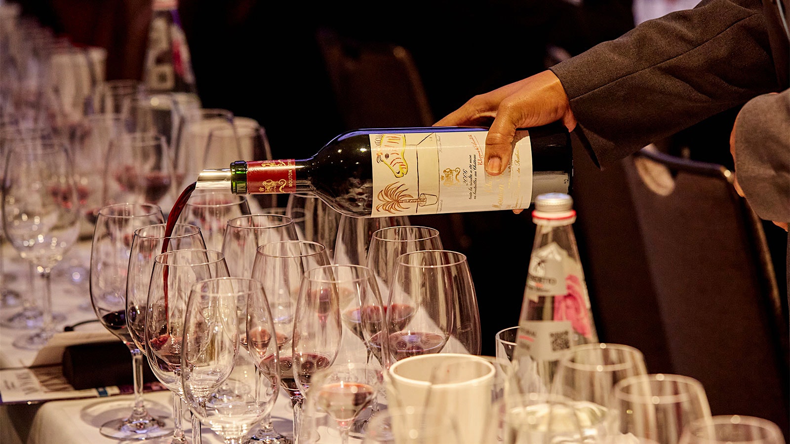 Server pouring a bottle of Château Mouton-Rothschild 2006, with an artist label from Lucien Freud, for a guest at the 2022 New York Wine Experience